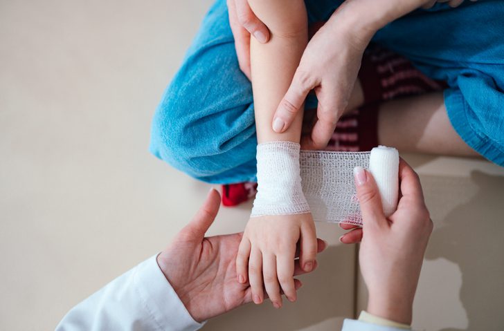 Adult wrapping bandage around child's wrist